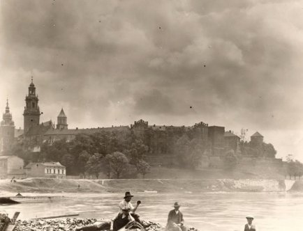 Zdjęcie w sepii. Rzeka Wisła, łódź z ludźmi. W tle Wawel.