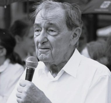 Czarno-biała fotografia. Mężczyzna przemawiający z mikrofonem.