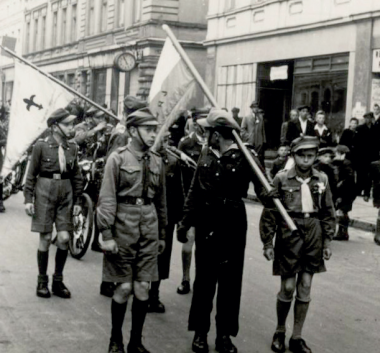 Czarno-biała fotografia. Mężczyźni z chorągwiami.