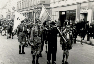 Czarno-biała fotografia. Mężczyźni z chorągwiami.